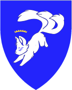 Device: (Fieldless) A three-tailed fox sejant erect argent charged on the shoulder with an annulet azure.